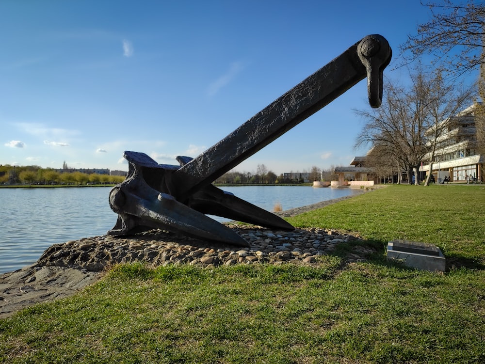 a sculpture of an anchor on a rock near a body of water