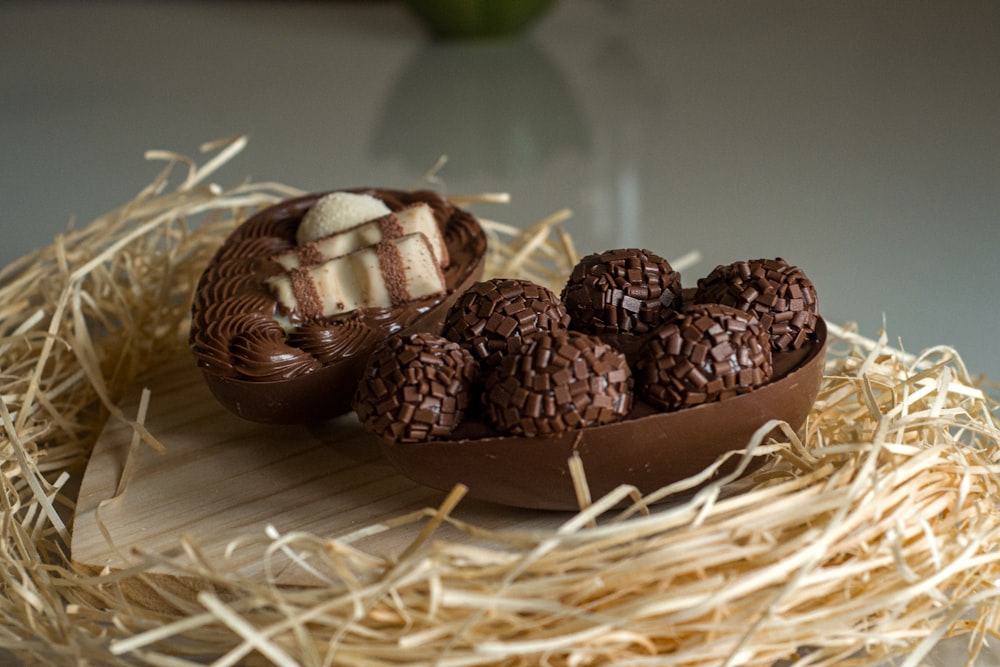 a plate of chocolates sitting on top of a pile of straw