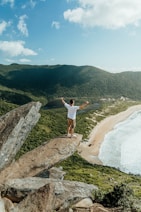 a man standing on top of a rock near the ocean