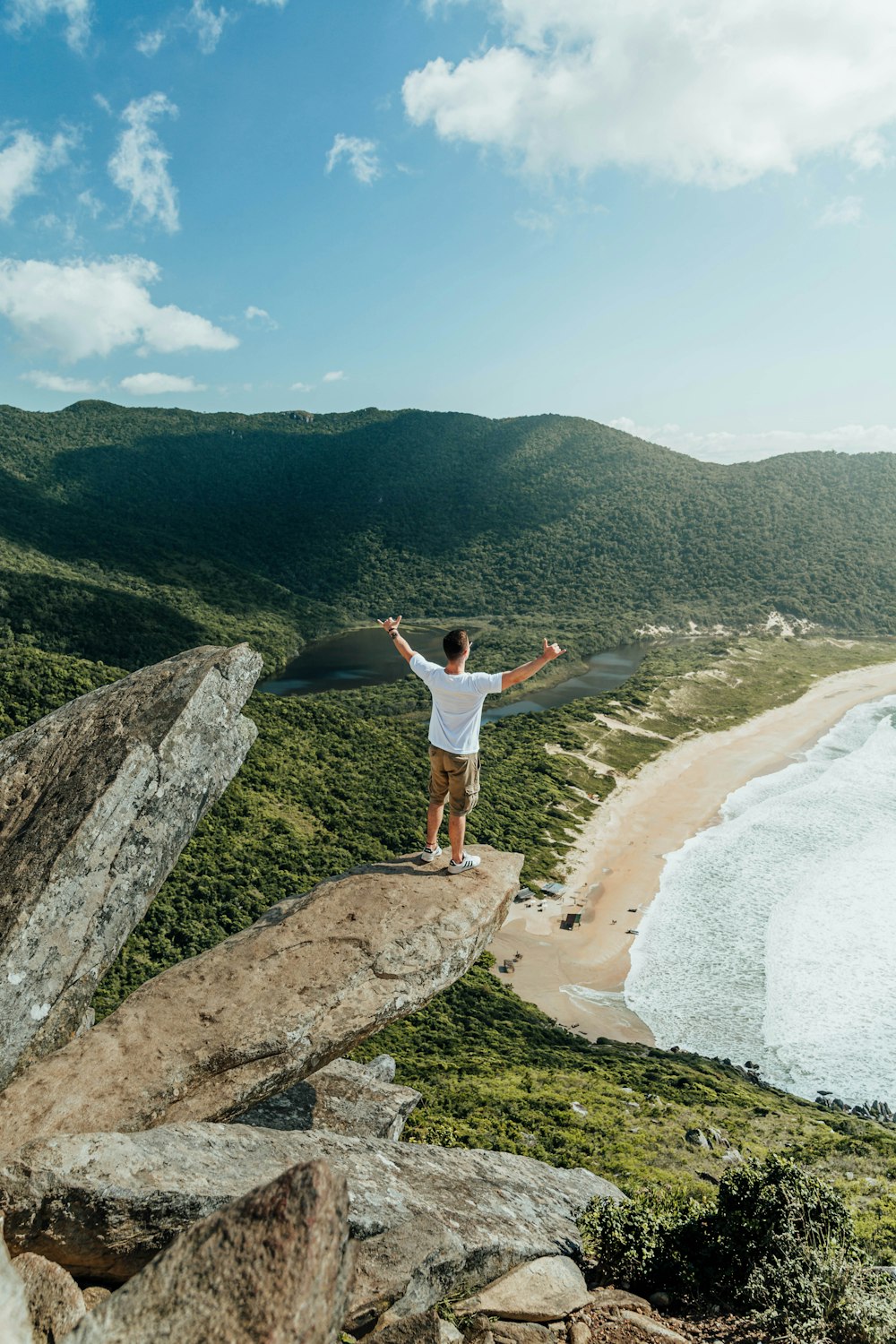 Un homme debout au sommet d’un rocher près de l’océan