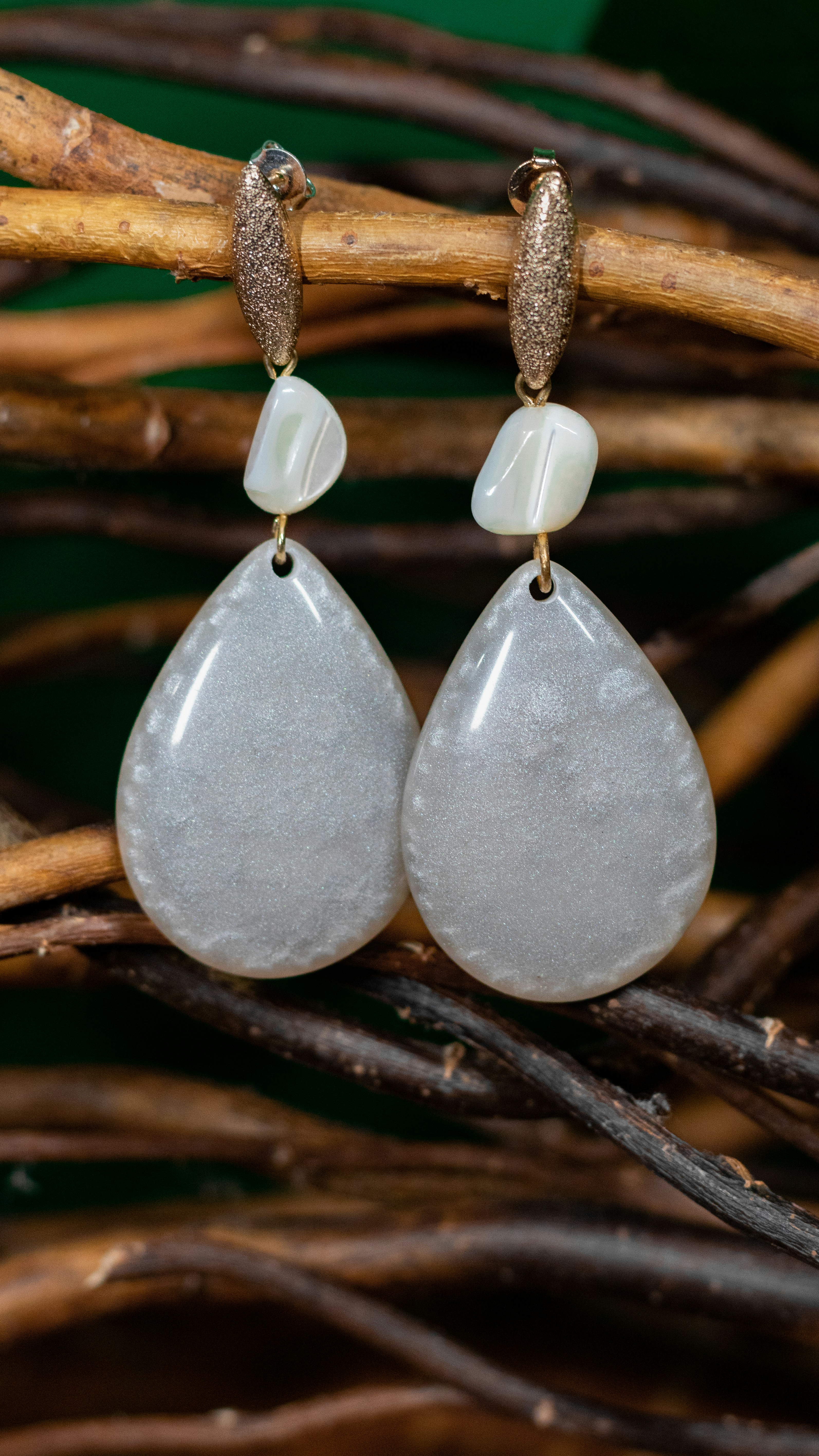 Athena earrings hanging from an olive branch, capturing the sacred essence of wisdom