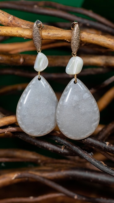 A pair of handmade earrings hanging from a natural branch.