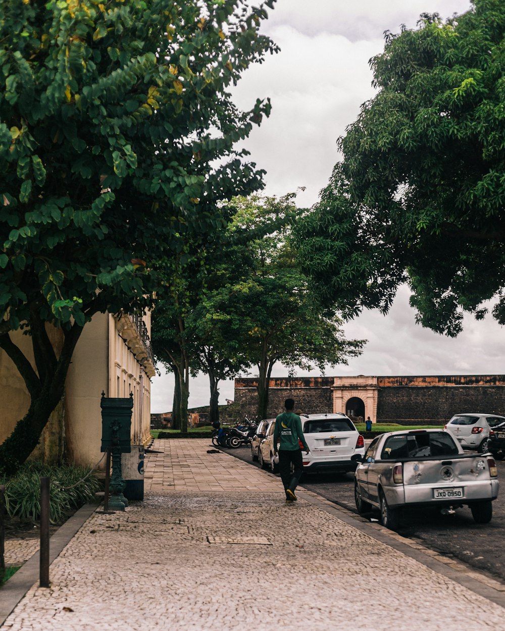 a man walking down a sidewalk next to parked cars