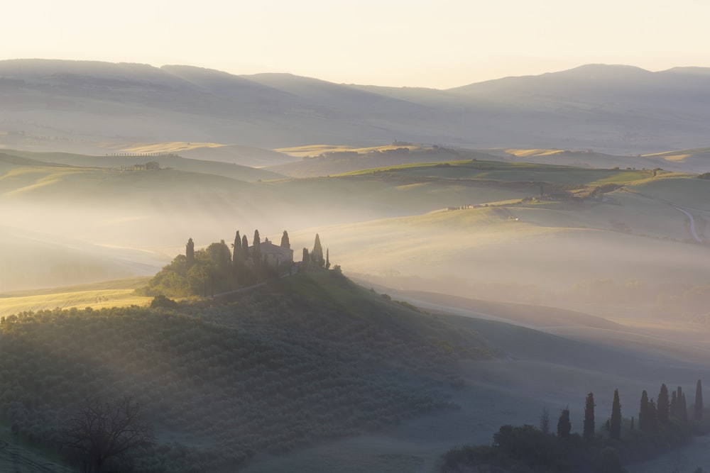 a foggy landscape with a castle on top of a hill