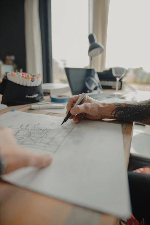 Designer drawing up a building design on paper at a desk with markers