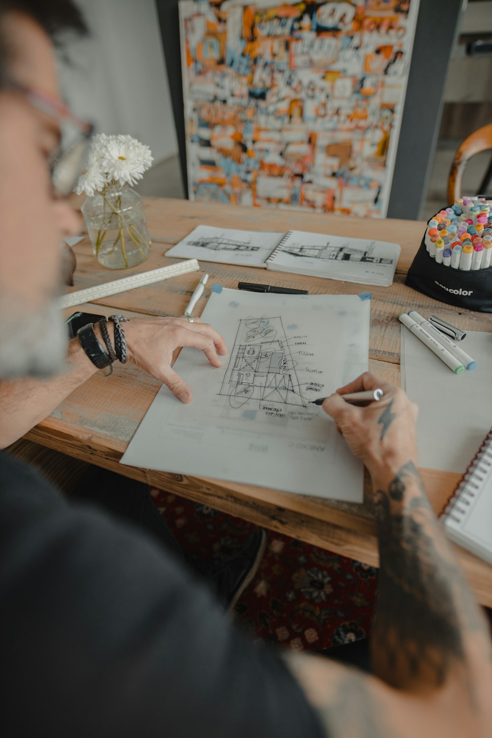 a man sitting at a desk drawing on a piece of paper