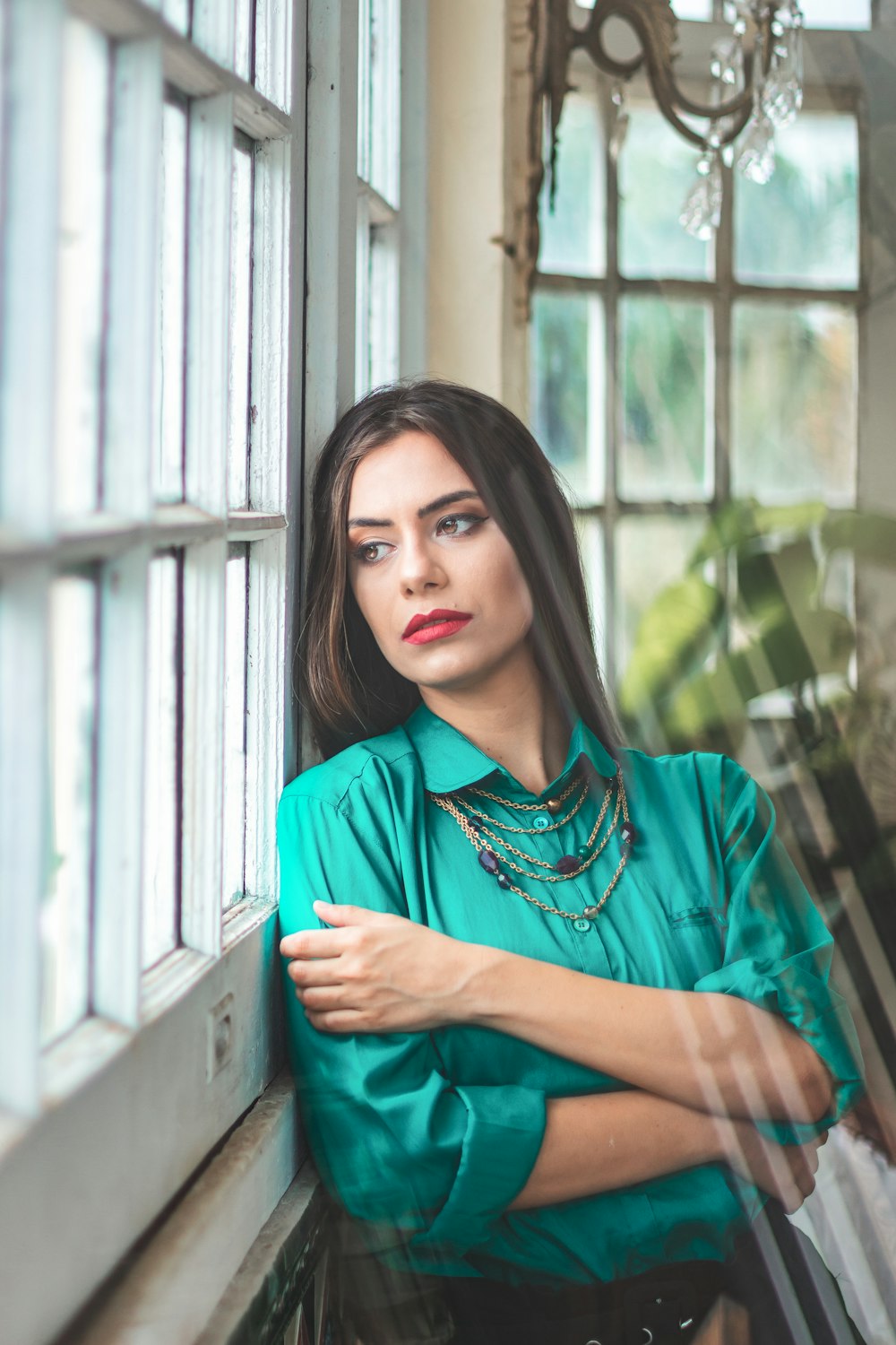 a woman leaning against a window with her arms crossed