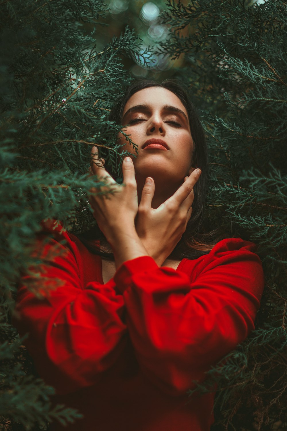 a woman in a red dress holding her hands up to her face