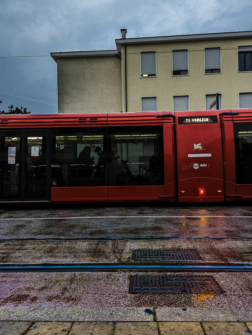 a red bus driving down a street next to a tall building