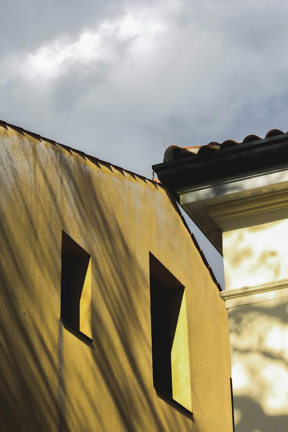 a yellow building with three windows and a sky background