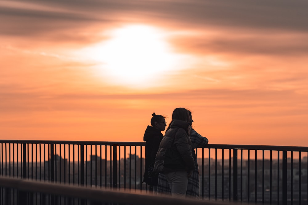 a couple of people standing on top of a bridge