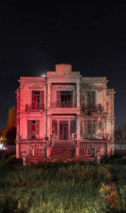 Close-up of a haunted mansion entrance illuminated by flickering lanterns at night.