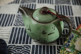 a green teapot with a red string on top of it