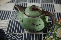 a green teapot with a red string on top of it