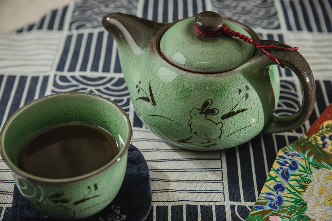 Green teapot and a small cup of tea