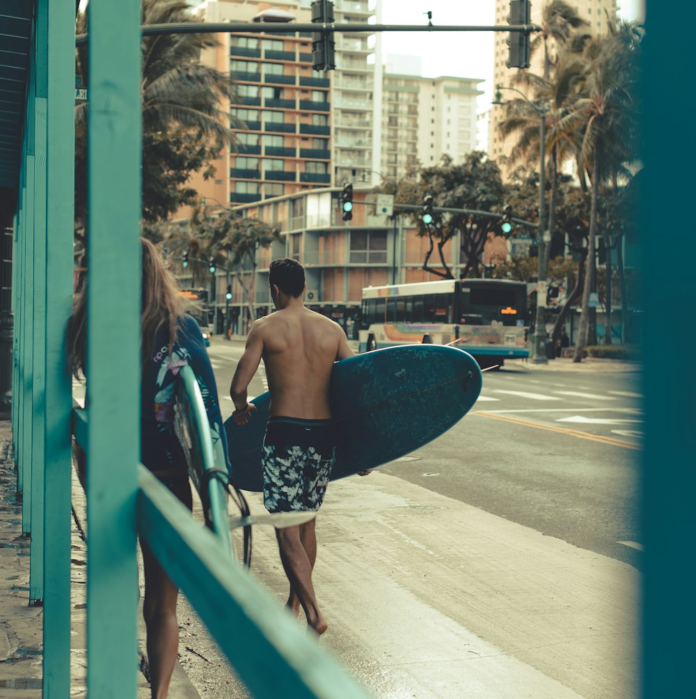 a man carrying a surfboard while walking down a street