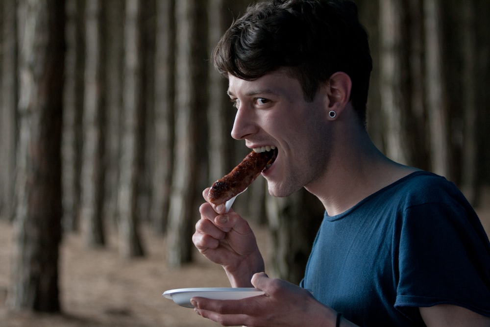 a man eating a hot dog in a forest