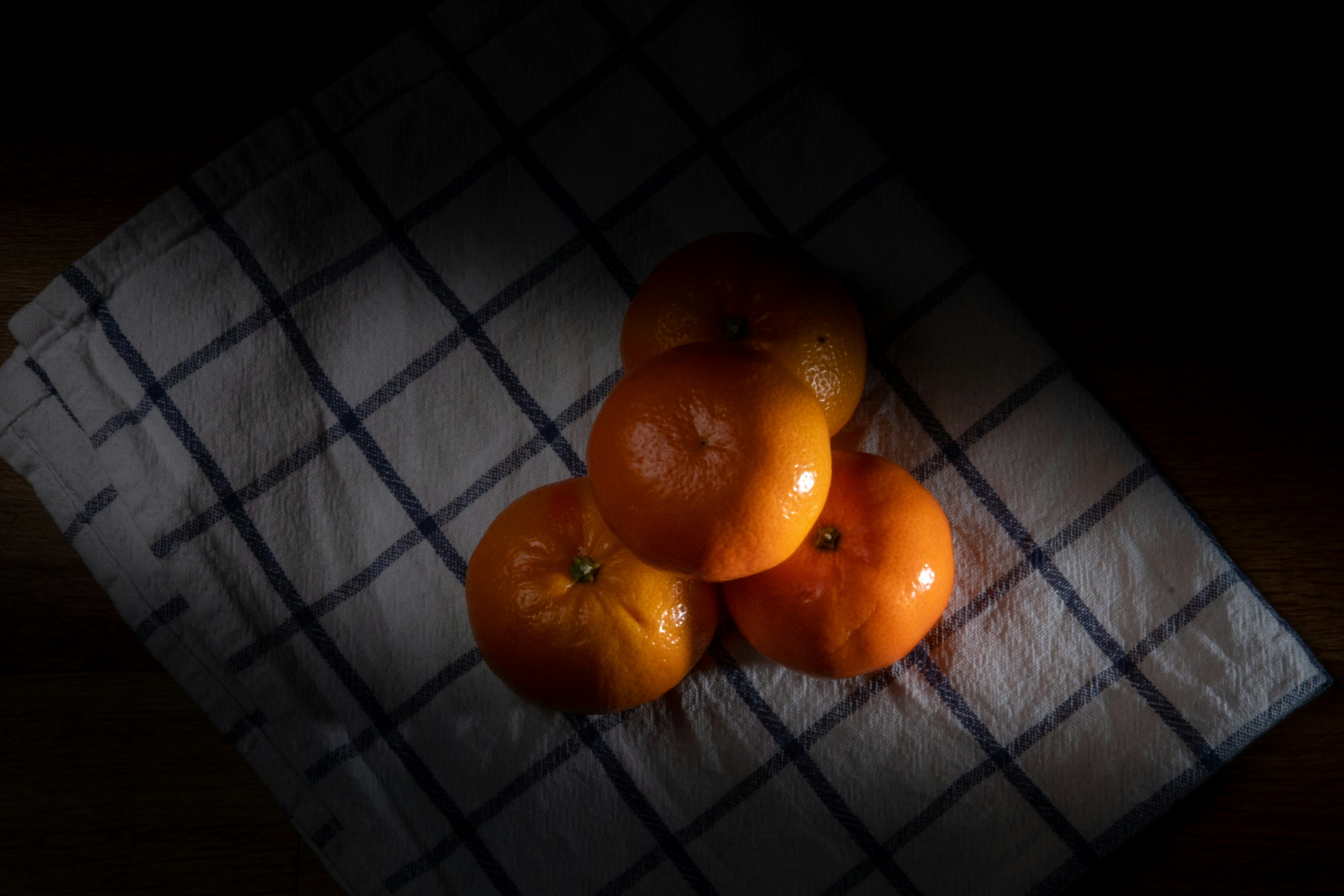 three oranges sitting on a towel on a table