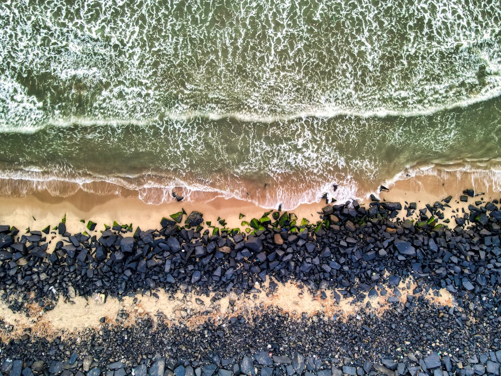 an aerial view of a beach with rocks and water