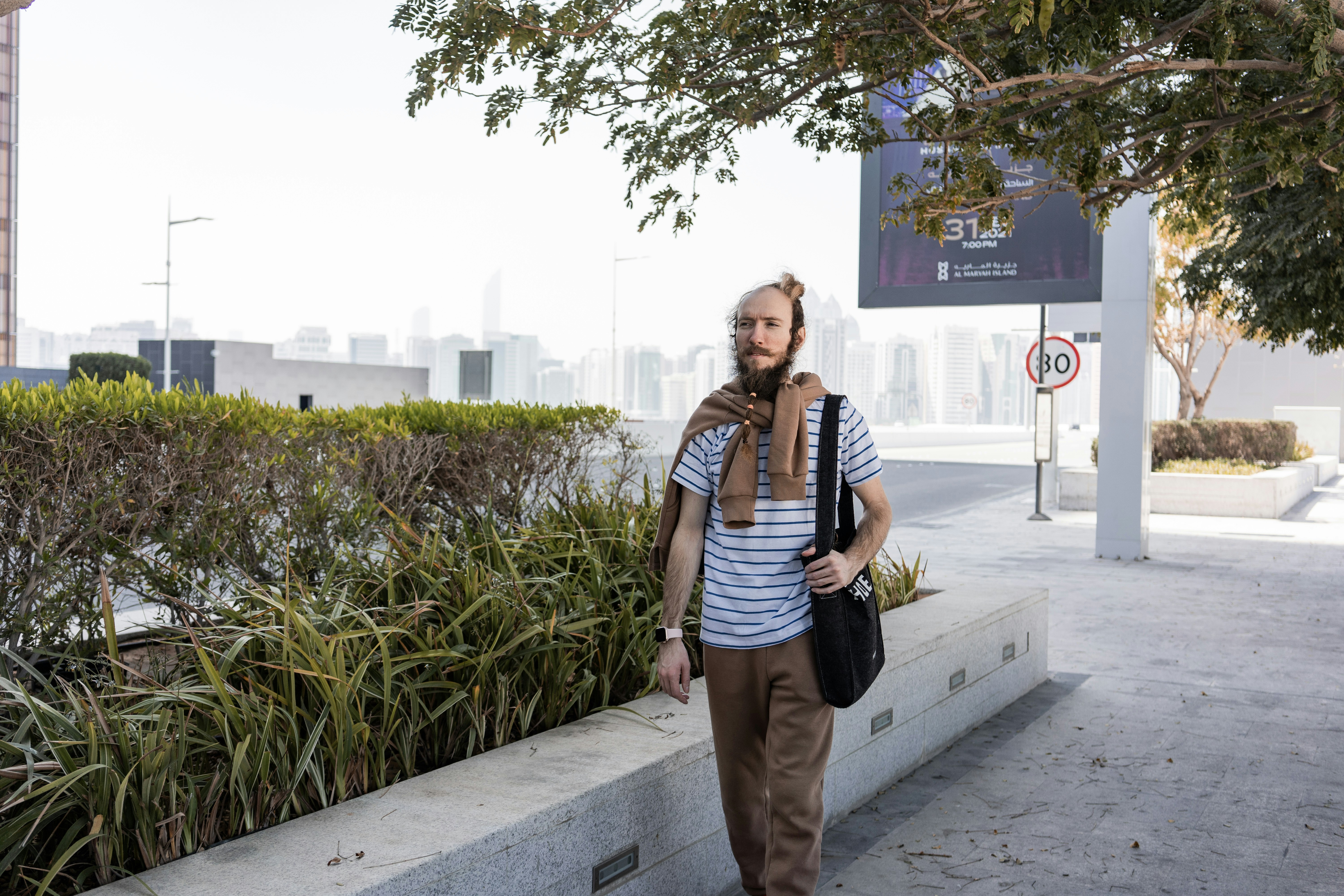 a man walking down a sidewalk with a scarf around his neck