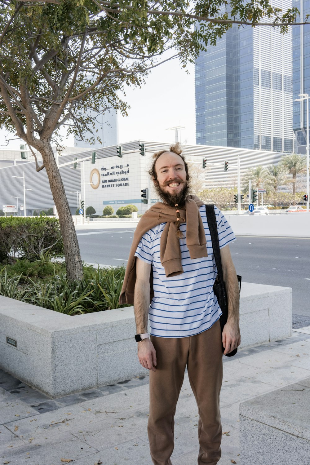 a man standing on a sidewalk with a scarf around his neck
