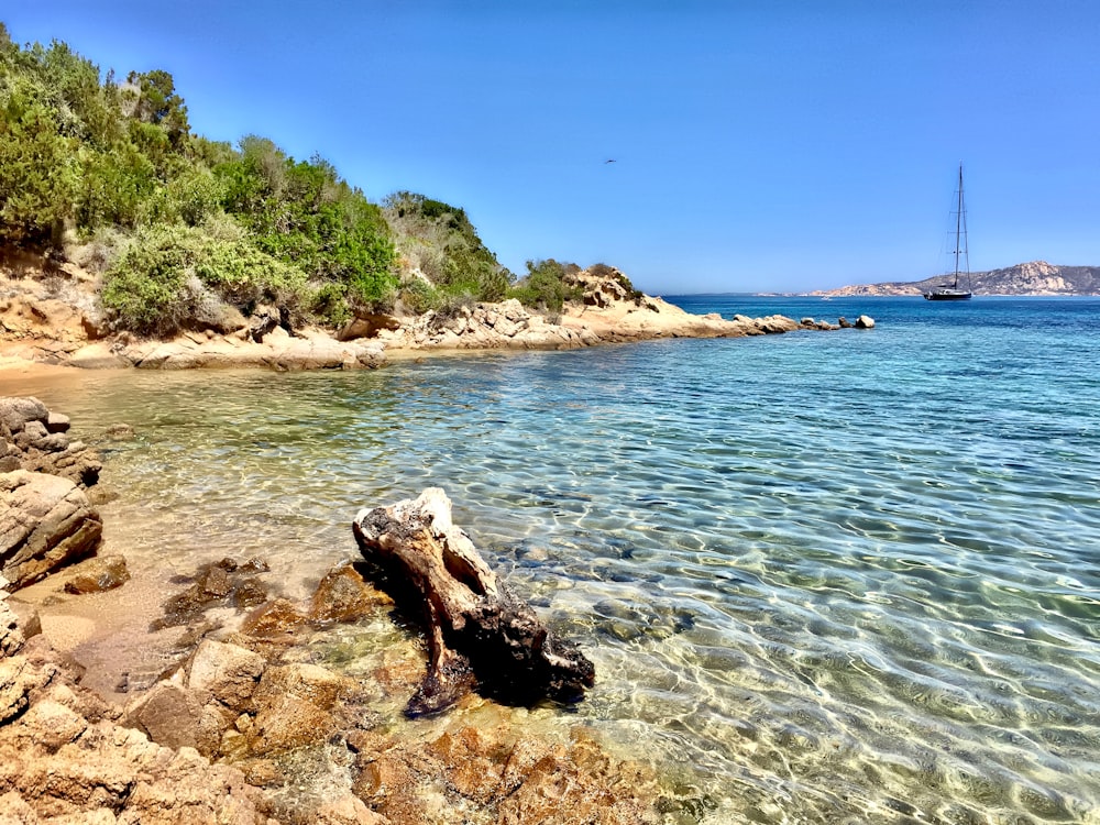 a boat is in the water near a rocky shore