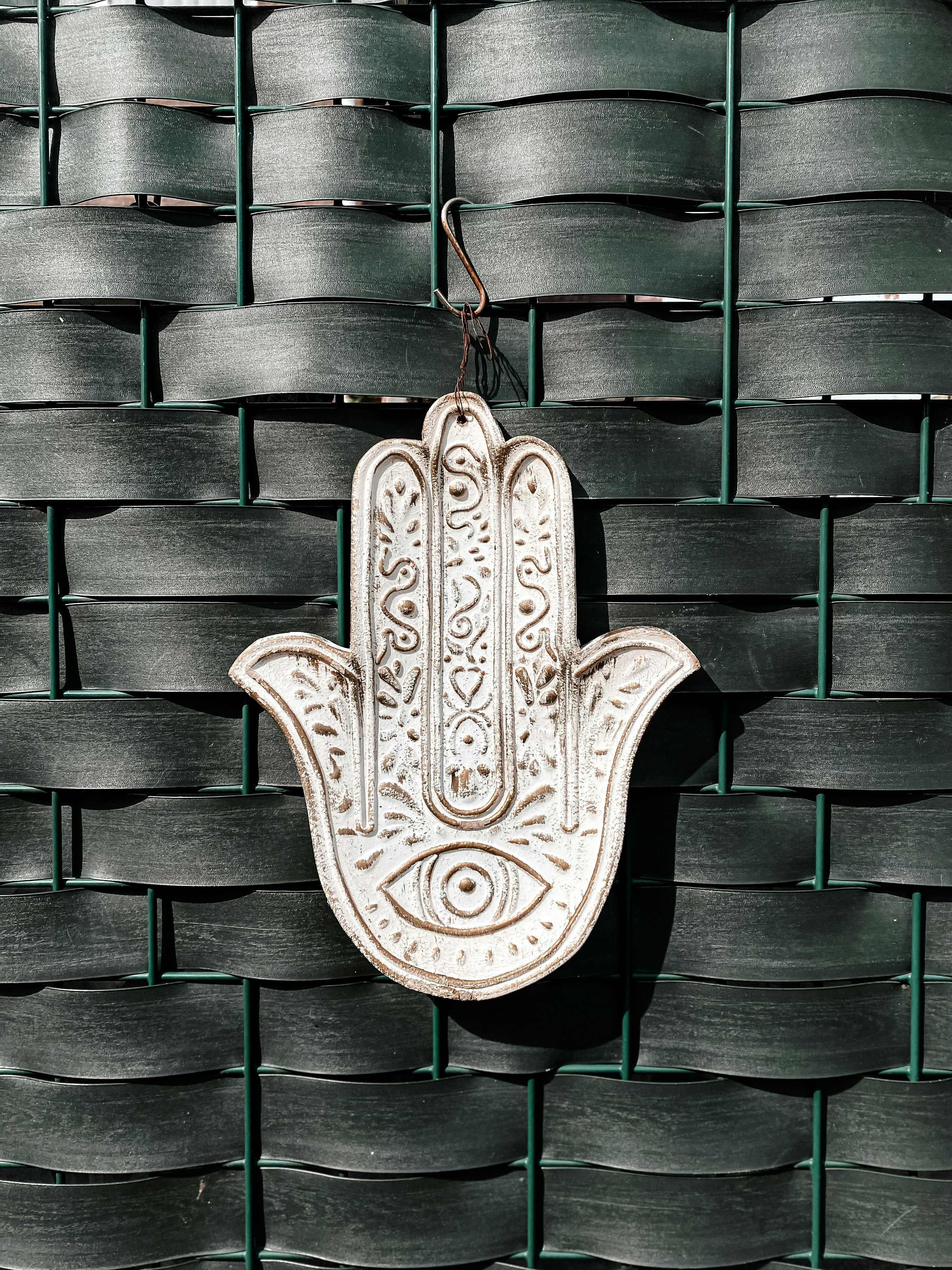 a hamsa hanging on a wall in front of a woven wall