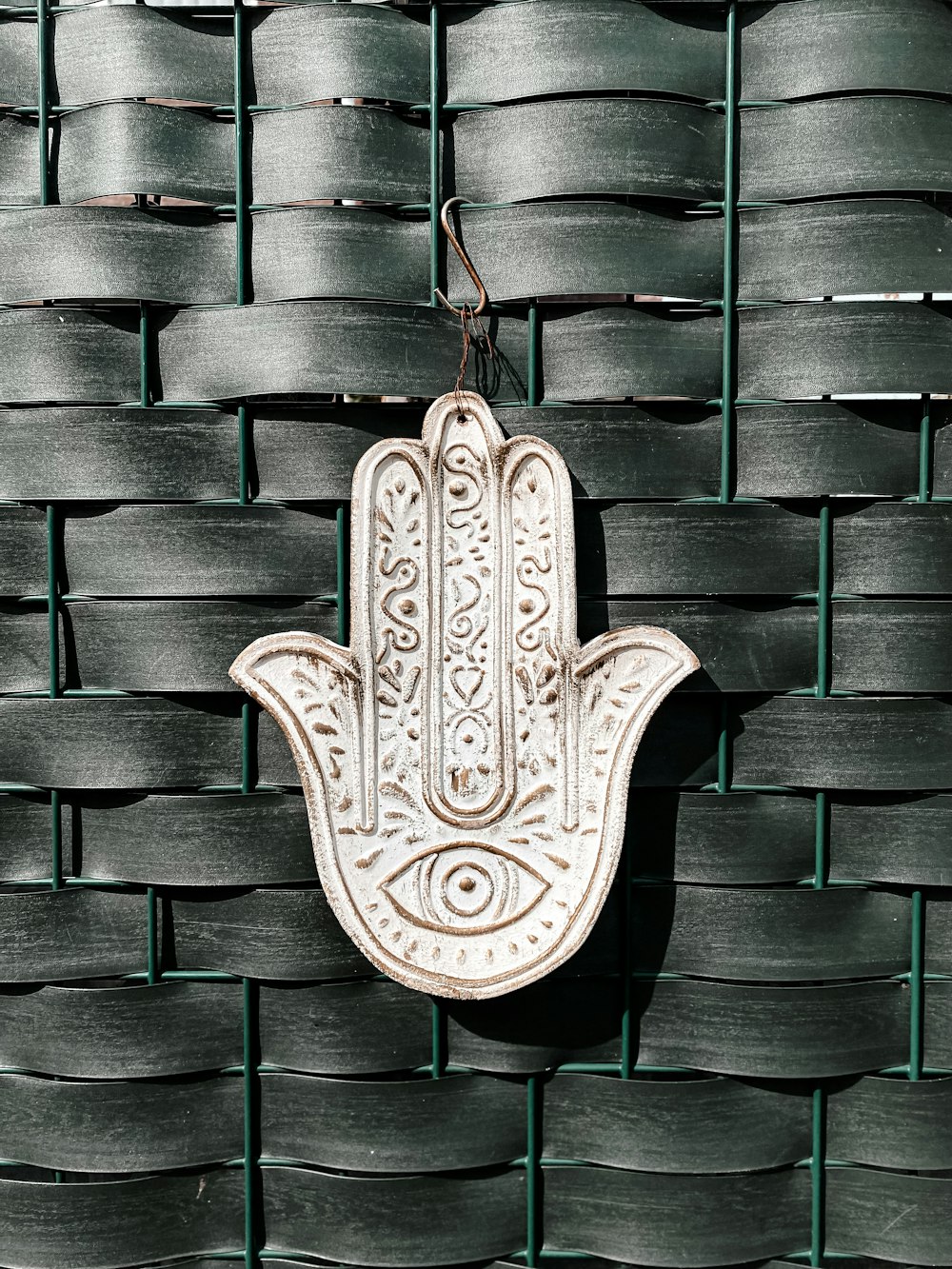 a hamsa hanging on a wall in front of a woven wall