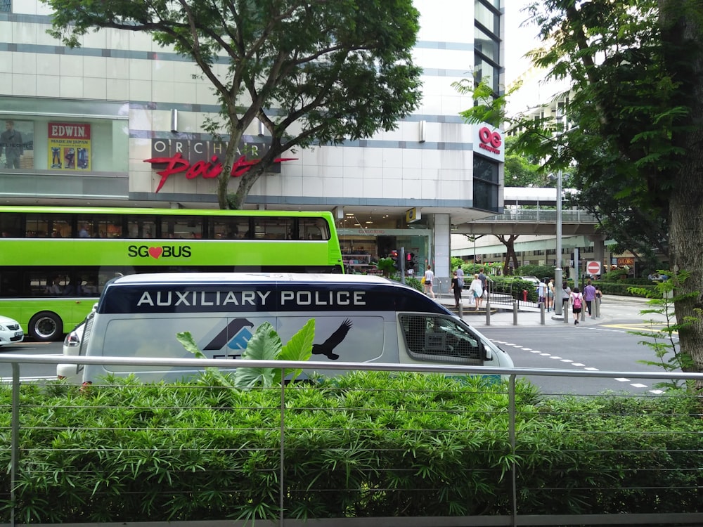 a green double decker bus driving down a street