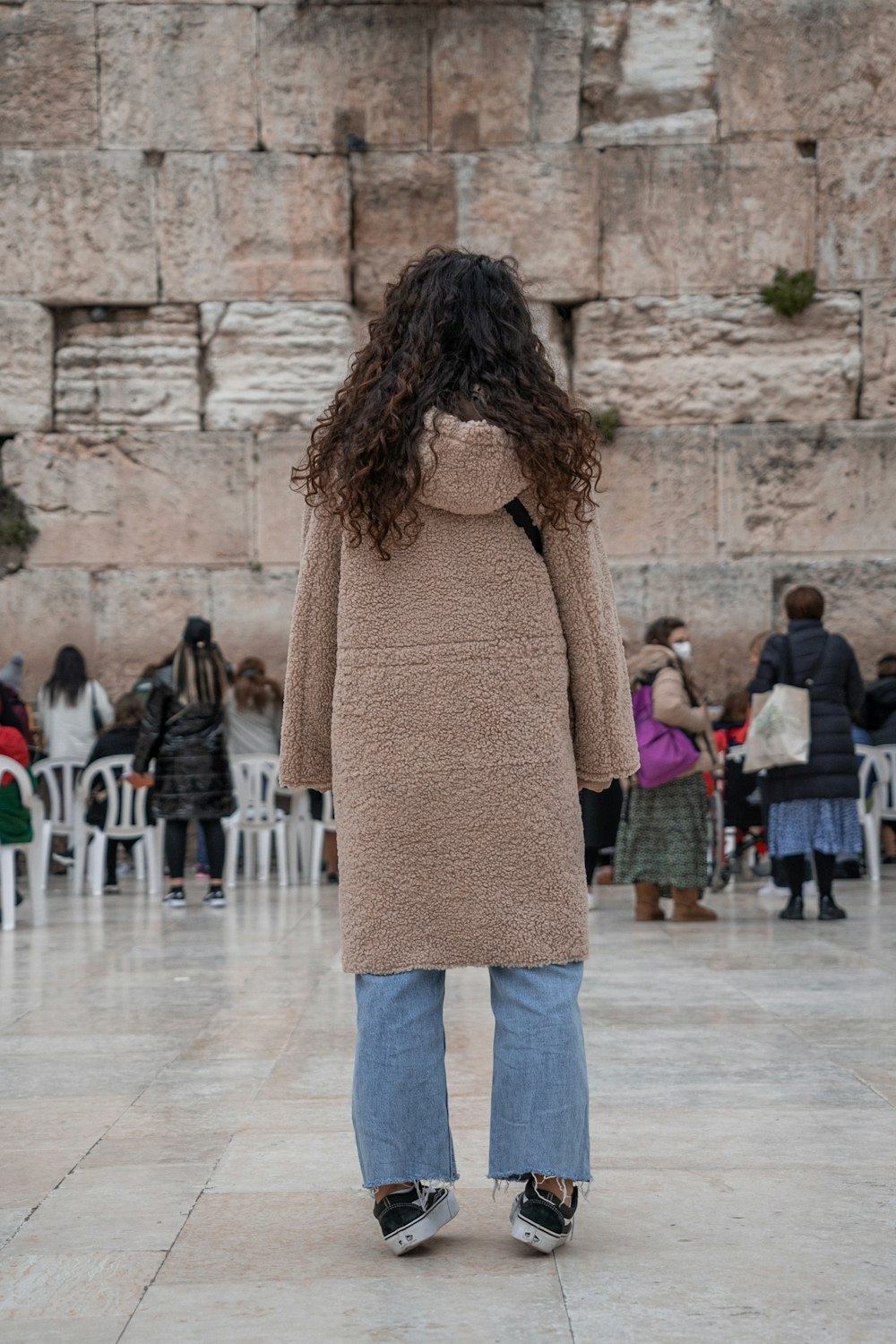 a woman standing in front of a stone wall