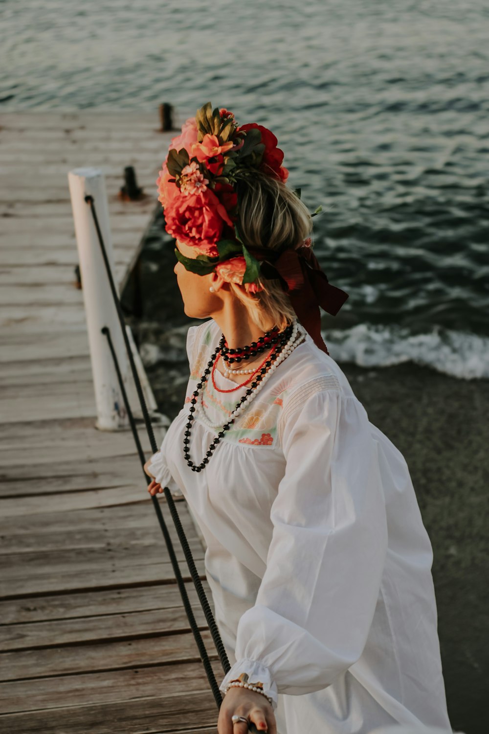 Una donna in piedi su un molo con un fiore tra i capelli