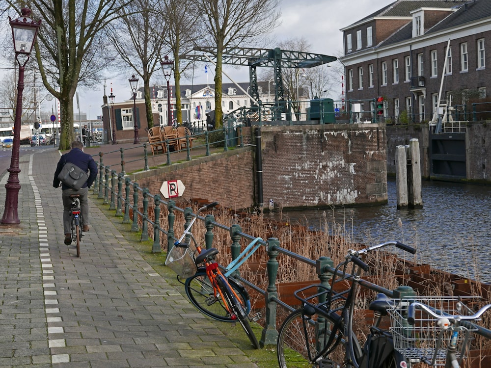 a man riding a bike down a street next to a river