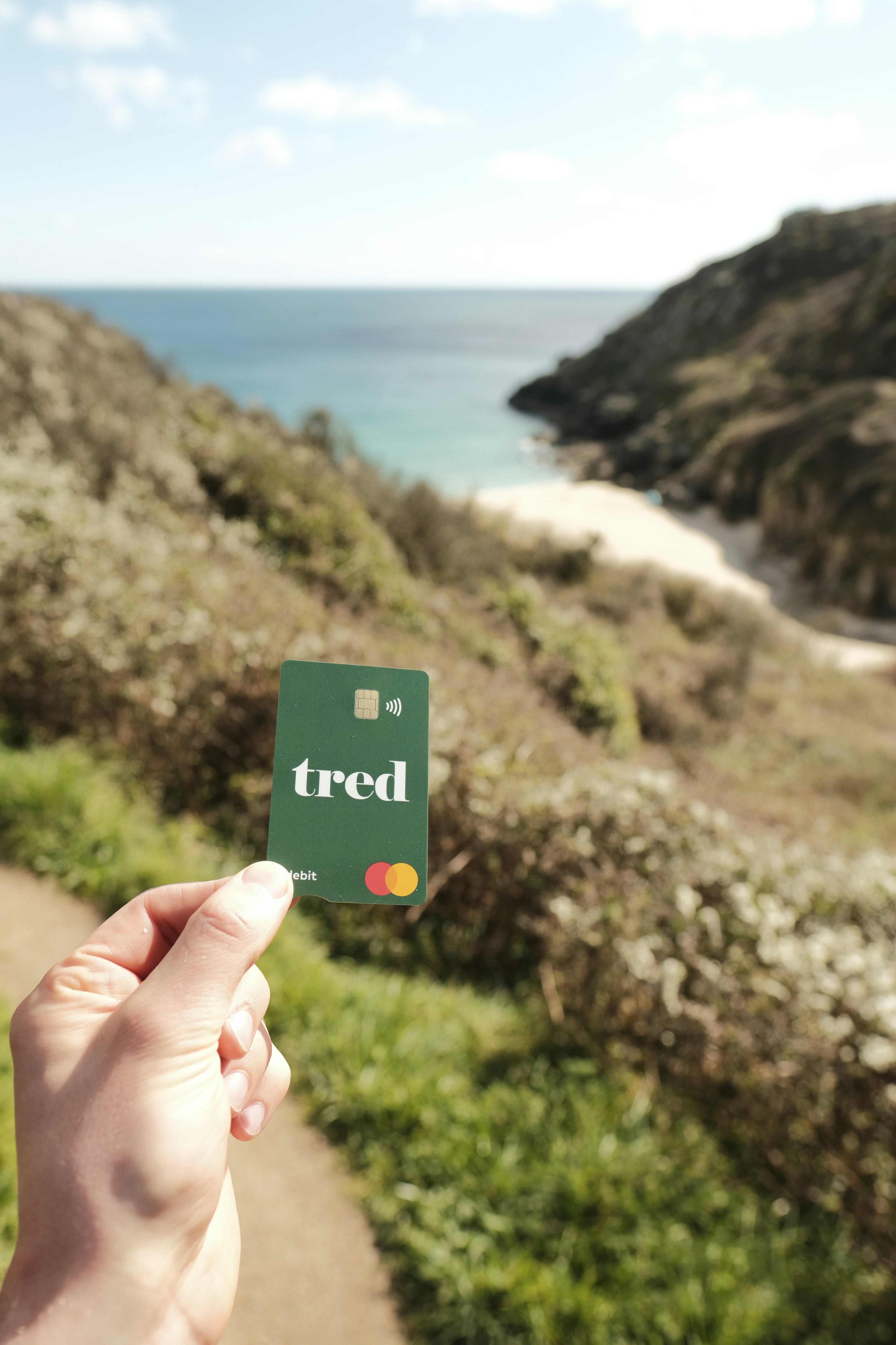 a person holding up a credit card in front of the ocean