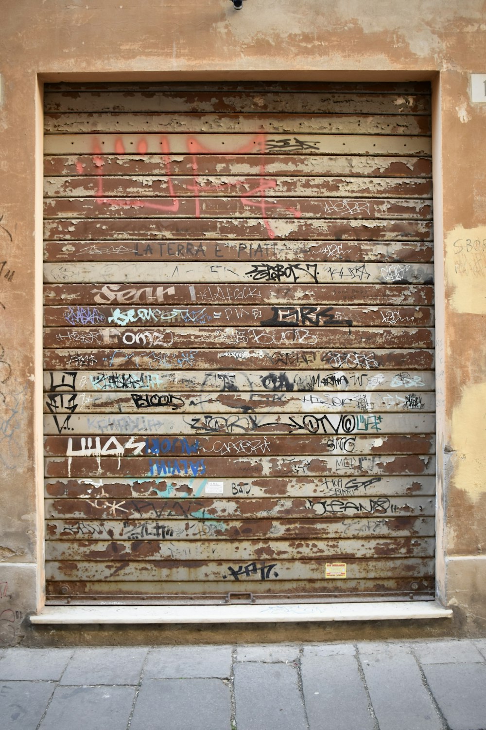 a garage door covered in graffiti on the side of a building