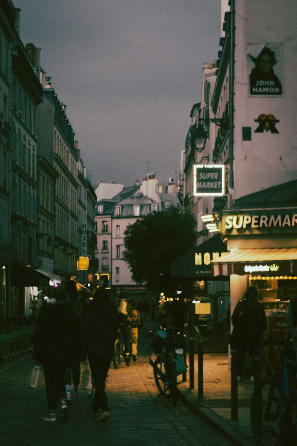 a group of people walking down a street next to tall buildings