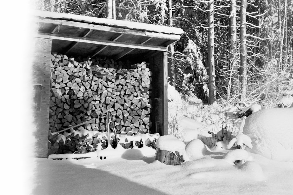 a pile of logs sitting in the snow next to a building