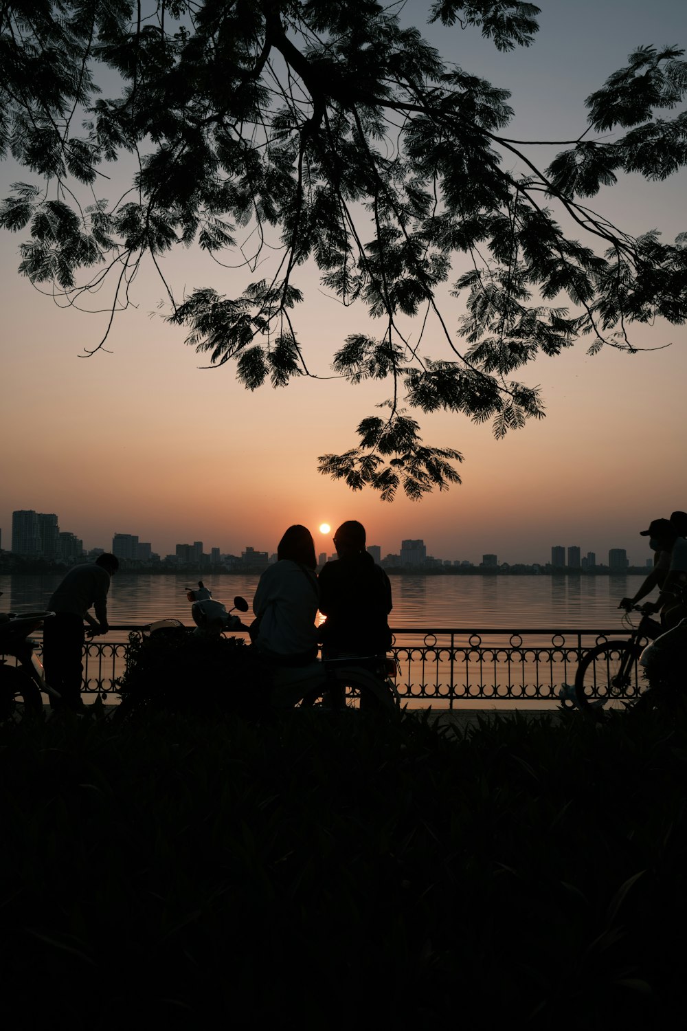 a group of people sitting on a bench next to a body of water