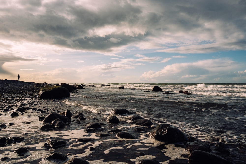 a person standing on a rocky beach next to the ocean