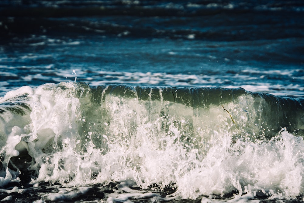 a large wave crashing into the shore of a beach