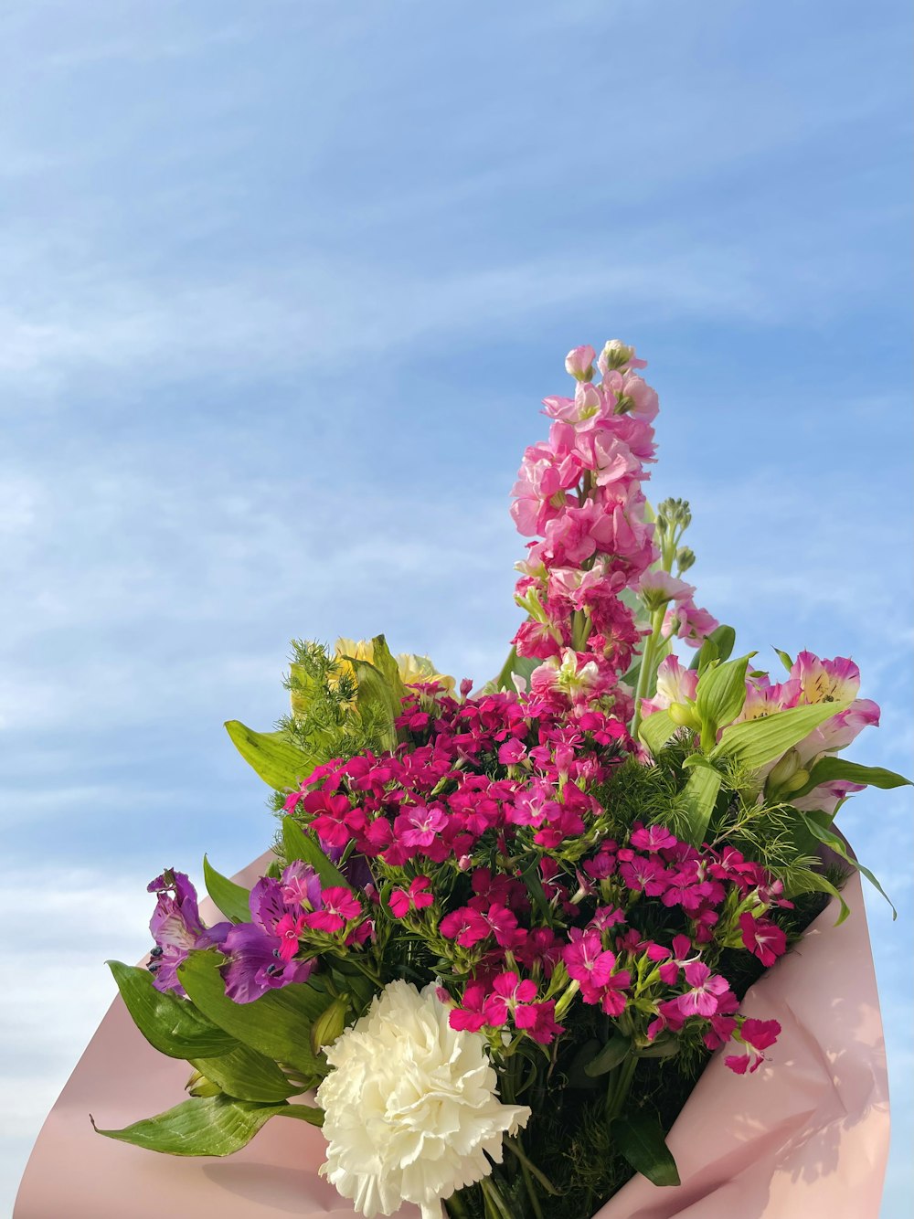 Un bouquet de fleurs est enveloppé dans du papier rose