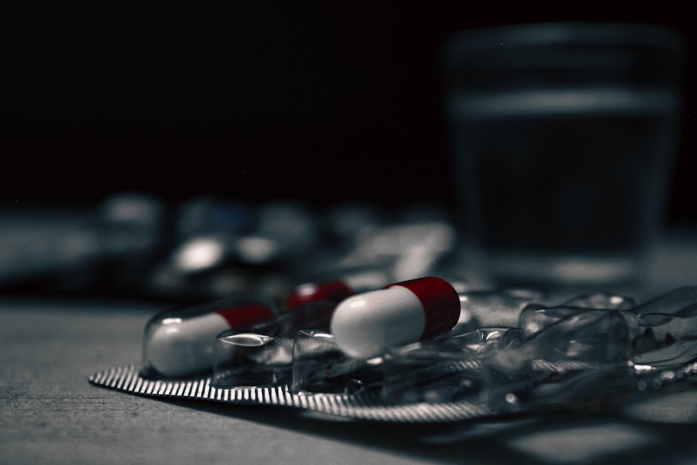 a close up of pills and a glass of water