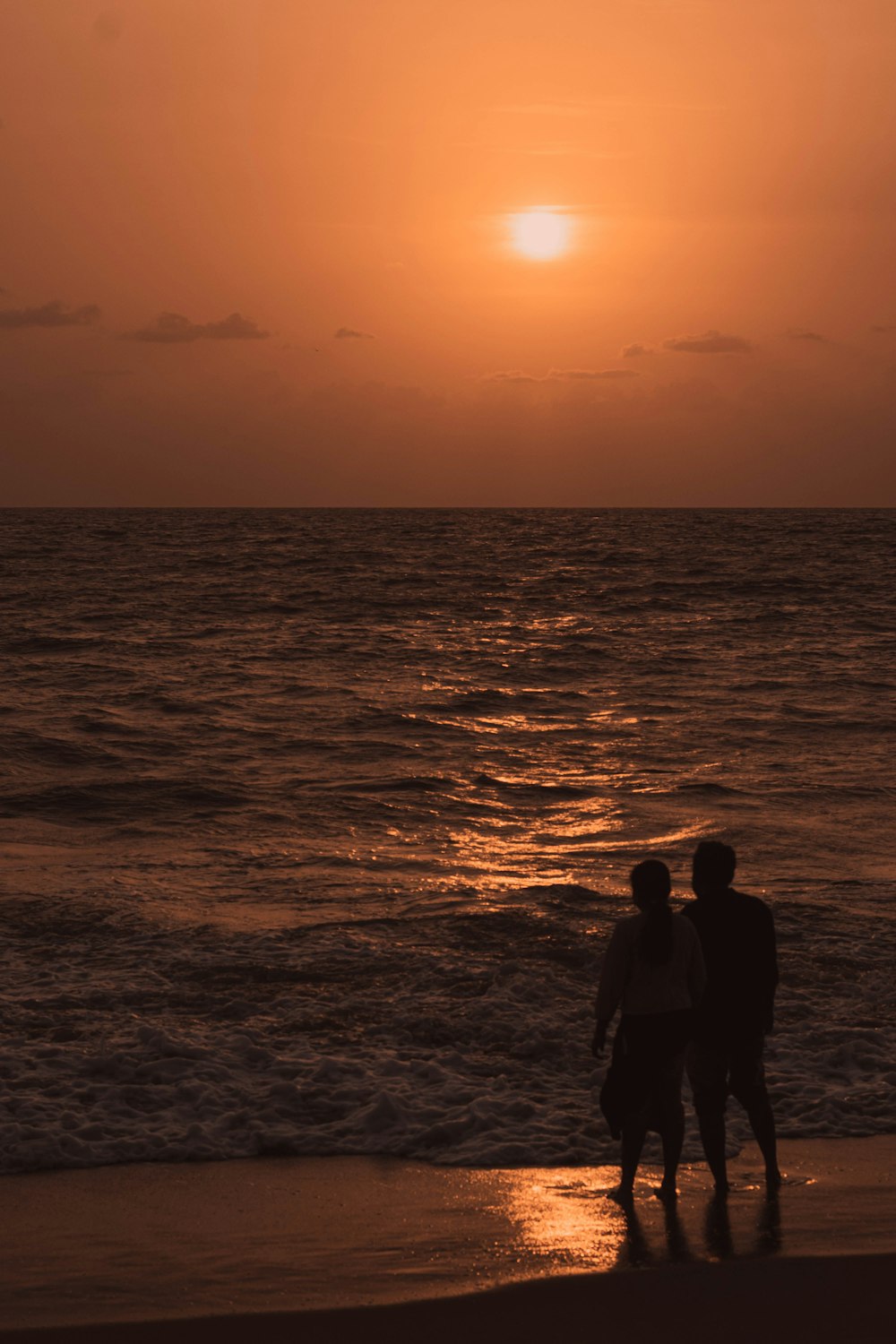 a couple of people standing on top of a beach