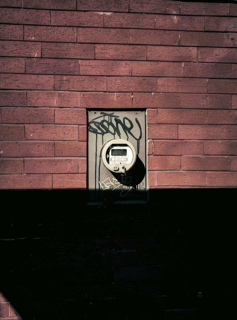 a brick wall with graffiti on it and a parking meter
