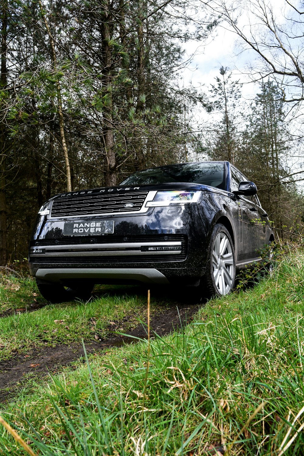 a range rover parked on a dirt road in the woods
