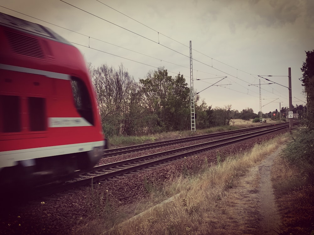 a red train traveling down train tracks next to a forest