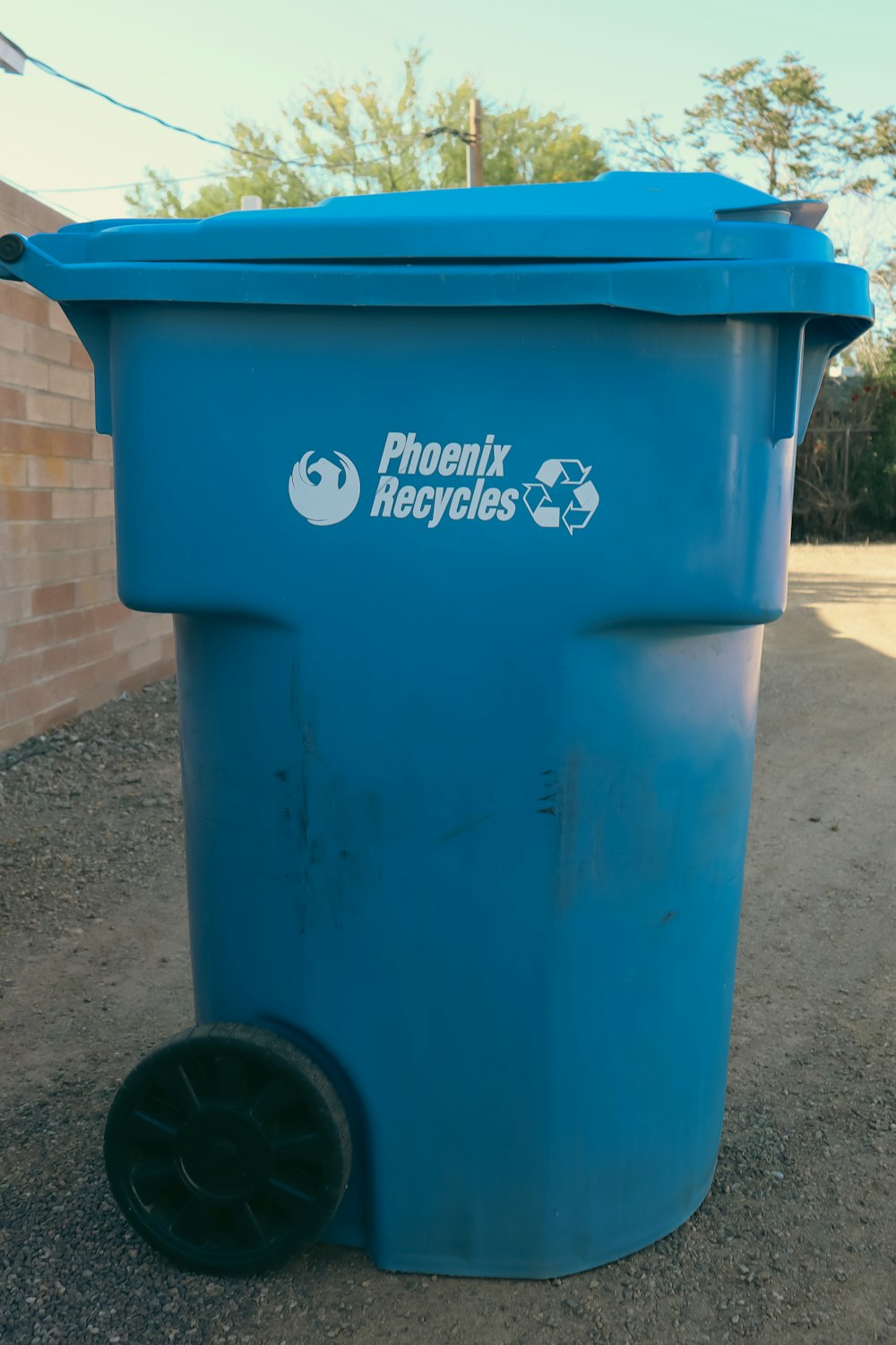 a blue trash can sitting on the side of a road