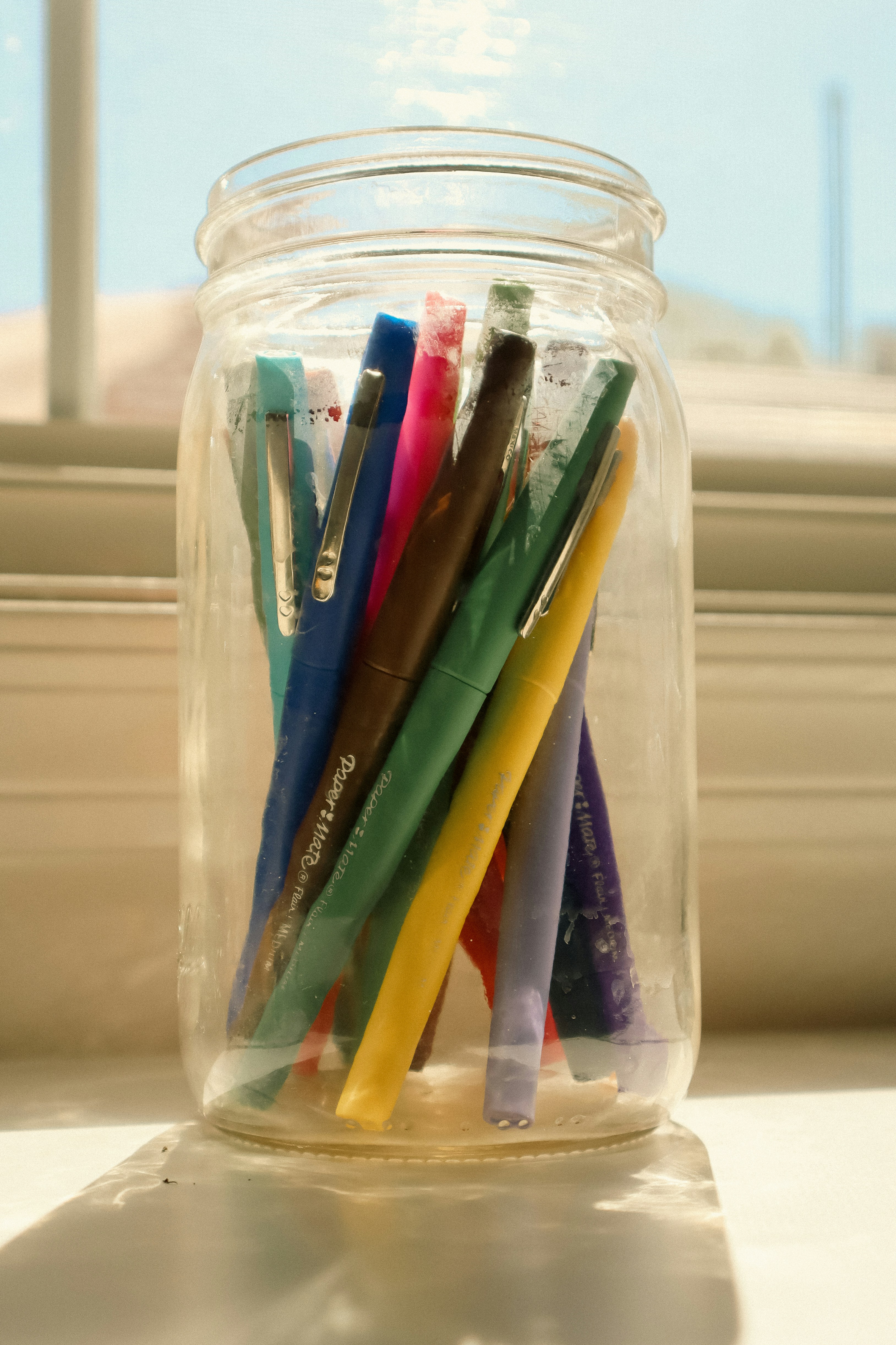 a jar filled with lots of different colored pens