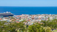 A panoramic view of a cruise ship docked at a bustling port city with colorful buildings.