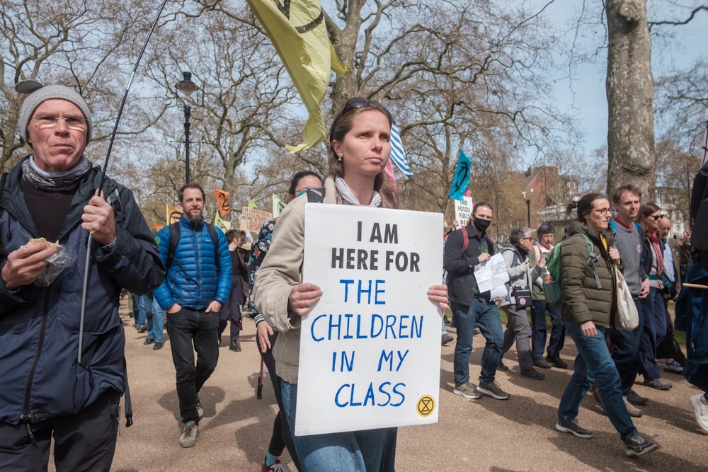 a group of people walking down a street holding signs