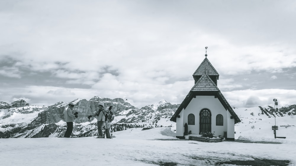 a black and white photo of two people standing in front of a church